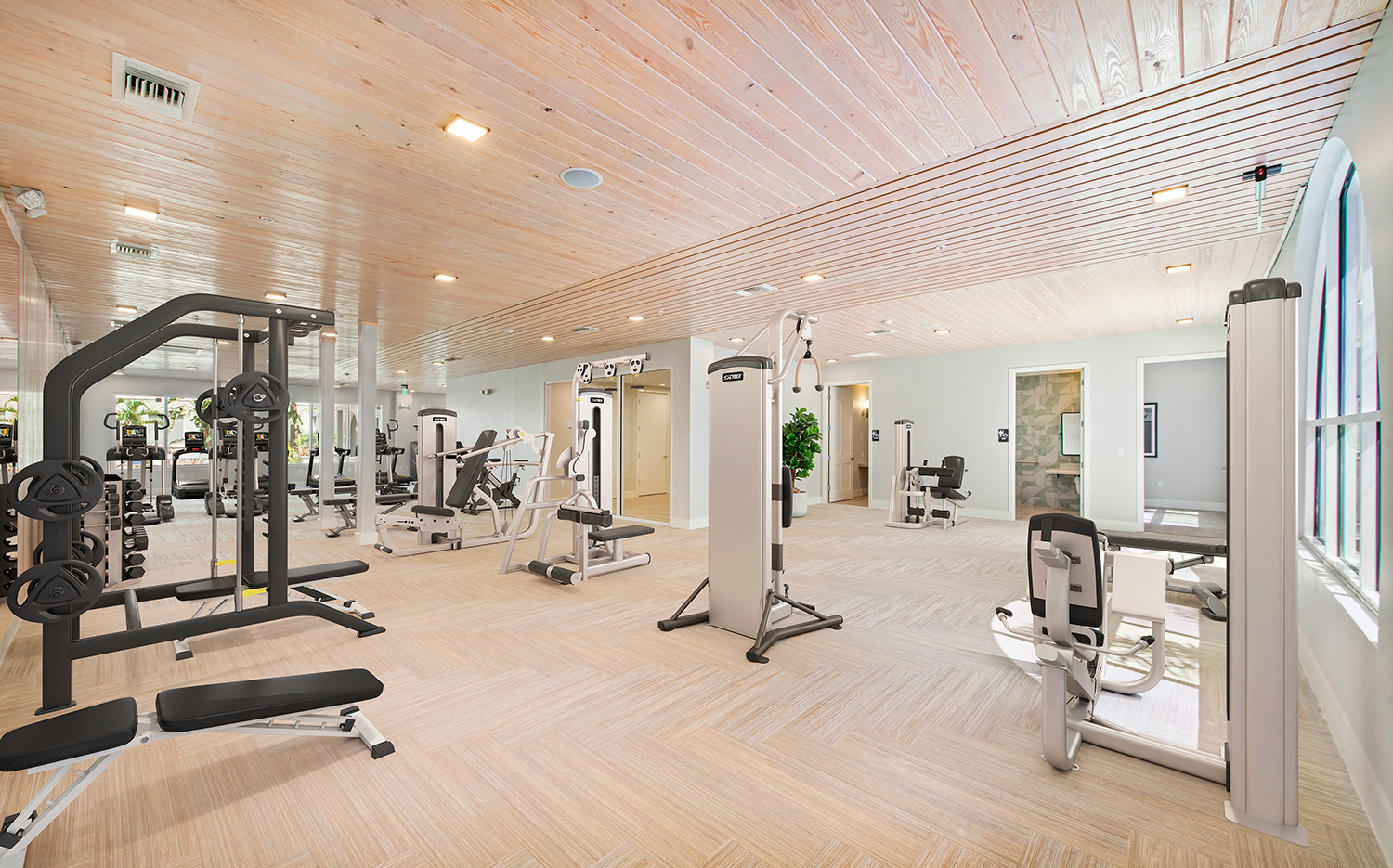 a gym with cardio equipment and weights in a building with wood floors