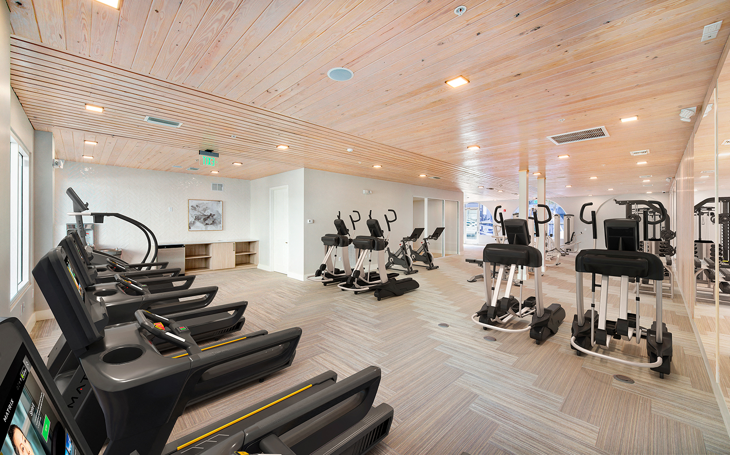 a gym with cardio machines and weights on a wooden floor