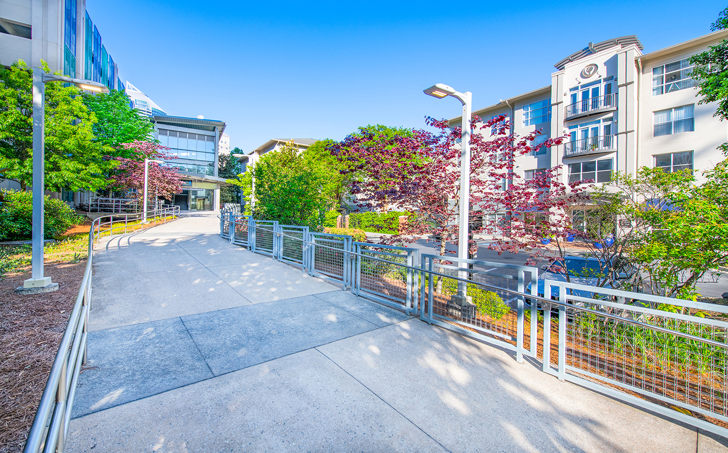 a sidewalk in front of a building with trees and a fence