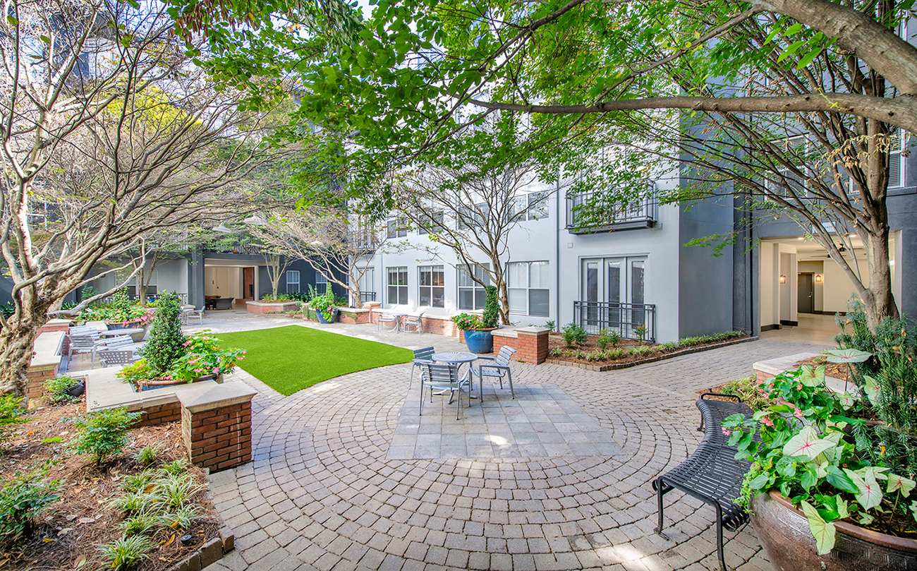 a courtyard with a table and chairs and a house in the background