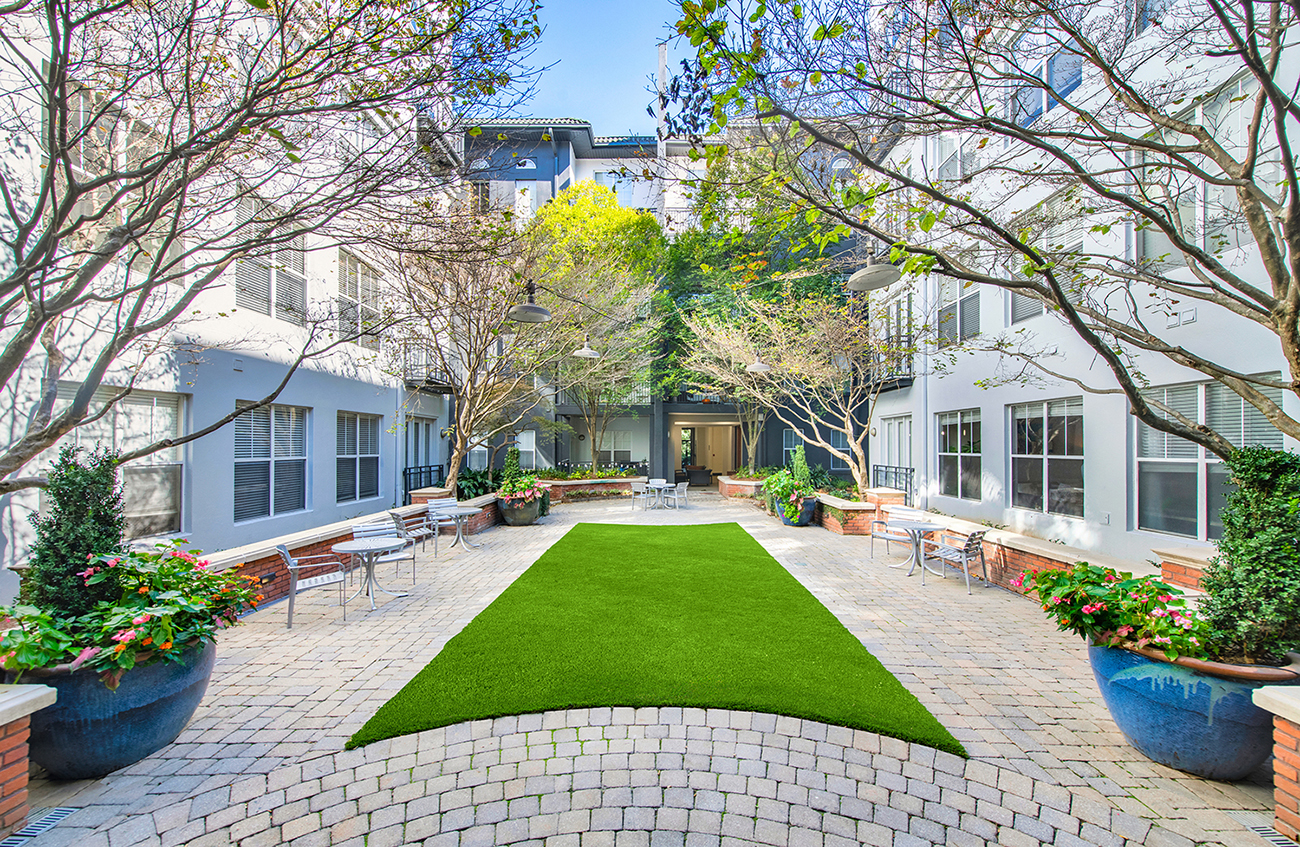 a courtyard with a green lawn in front of a house