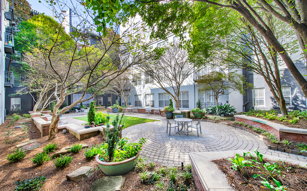 a courtyard with trees and a round patio with a table and chairs