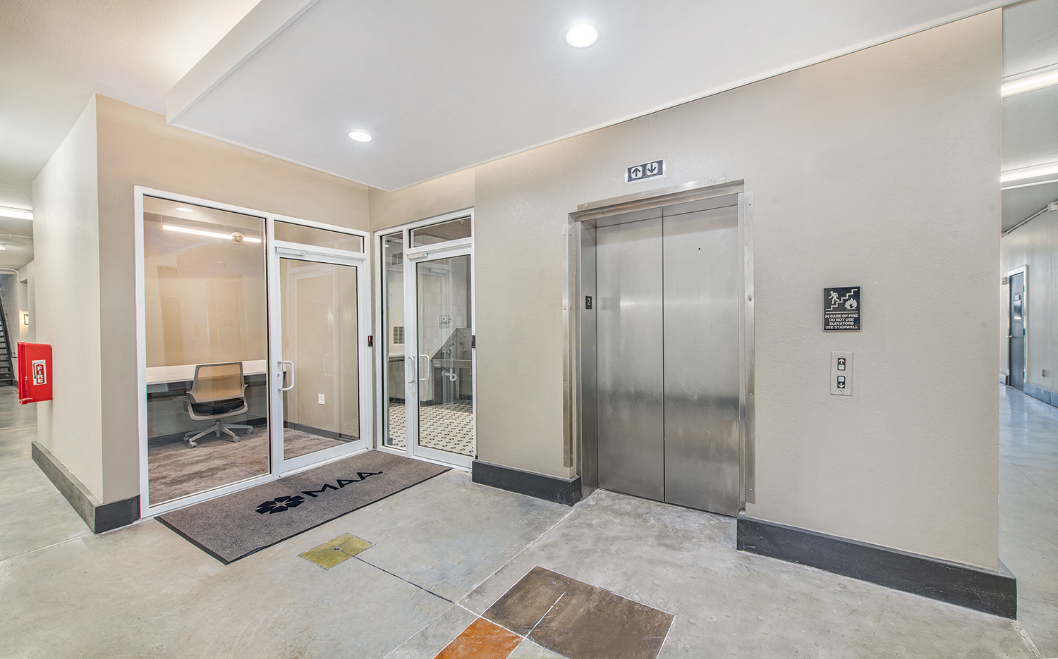 the lobby of a building with an elevator and glass doors