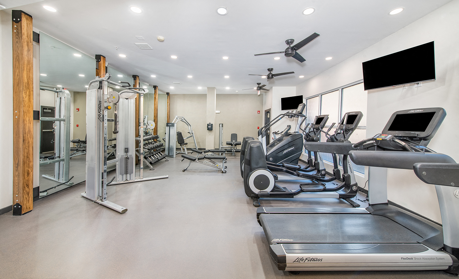a gym with cardio equipment and a flat screen tv