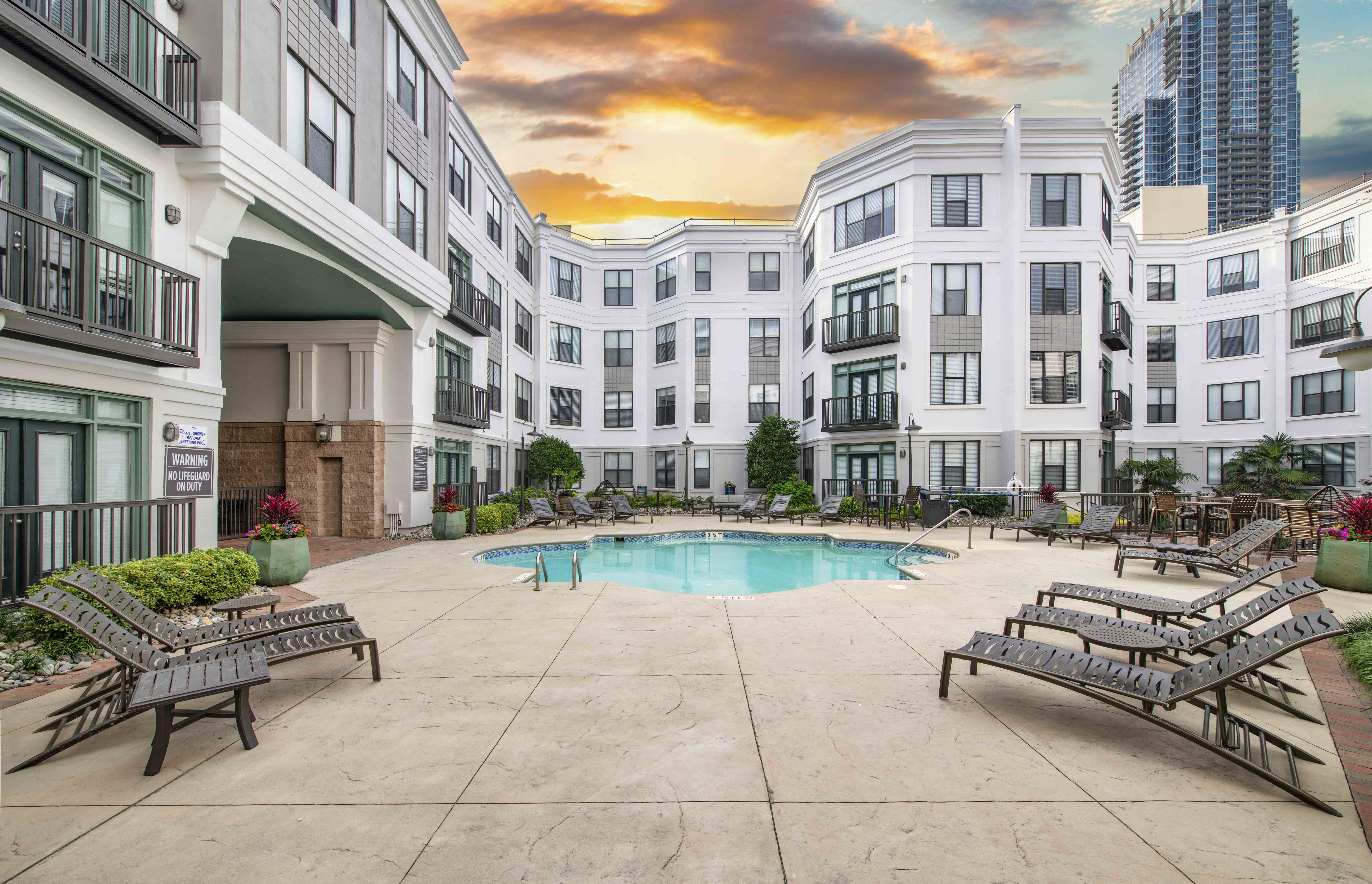 a swimming pool with benches around it in front of an apartment building