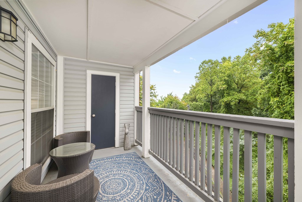 A balcony with a table and chairs overlooking a forest.