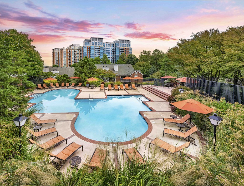 A large outdoor pool surrounded by wooden loungers and umbrellas.