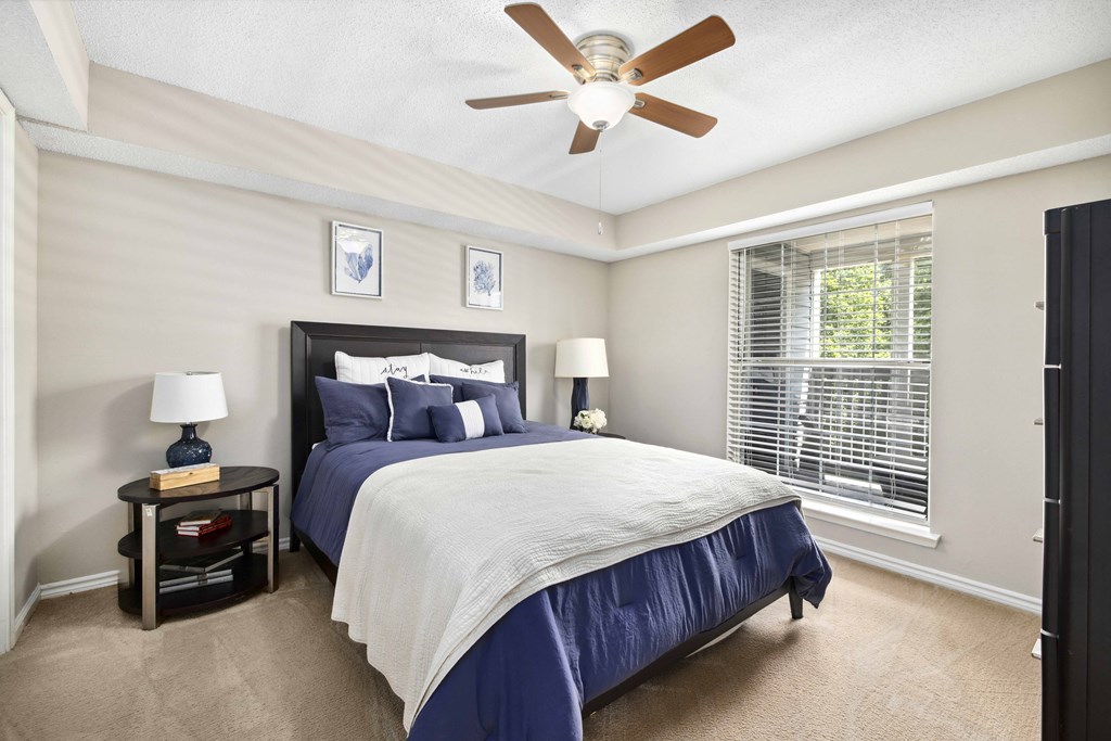A bedroom with a bed, nightstand, and a ceiling fan.