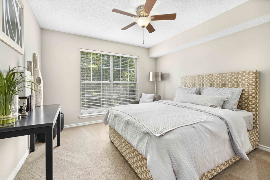 A bedroom with a large bed and a ceiling fan.