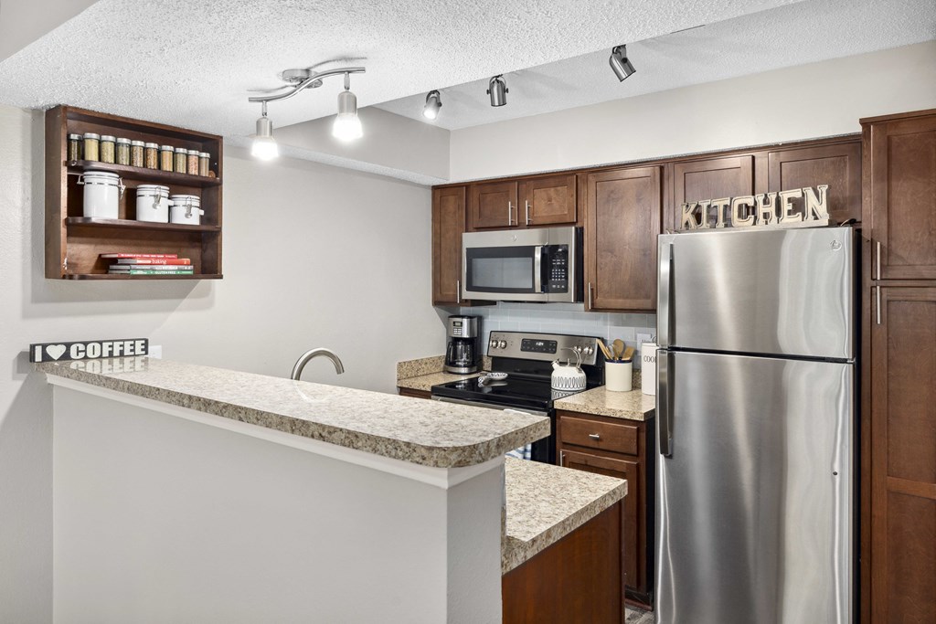 A kitchen with a refrigerator, microwave, and coffee sign.