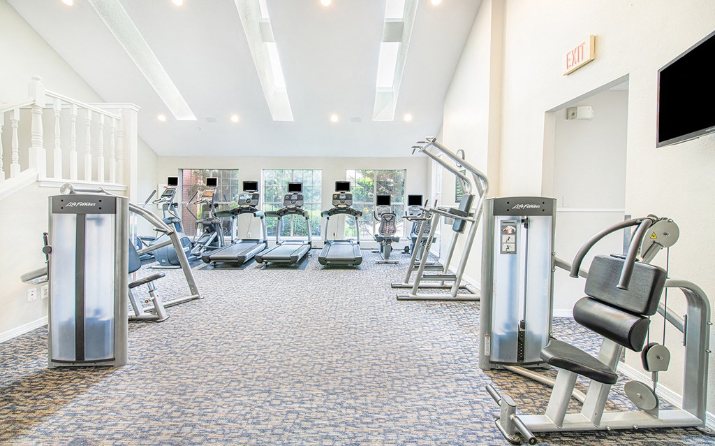 a gym with cardio equipment and weights on the floor
