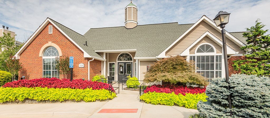 the front of a house with flowers and bushes in front of it