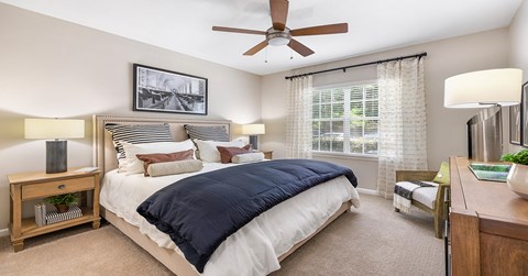 A bedroom with a bed, nightstand, and a ceiling fan.