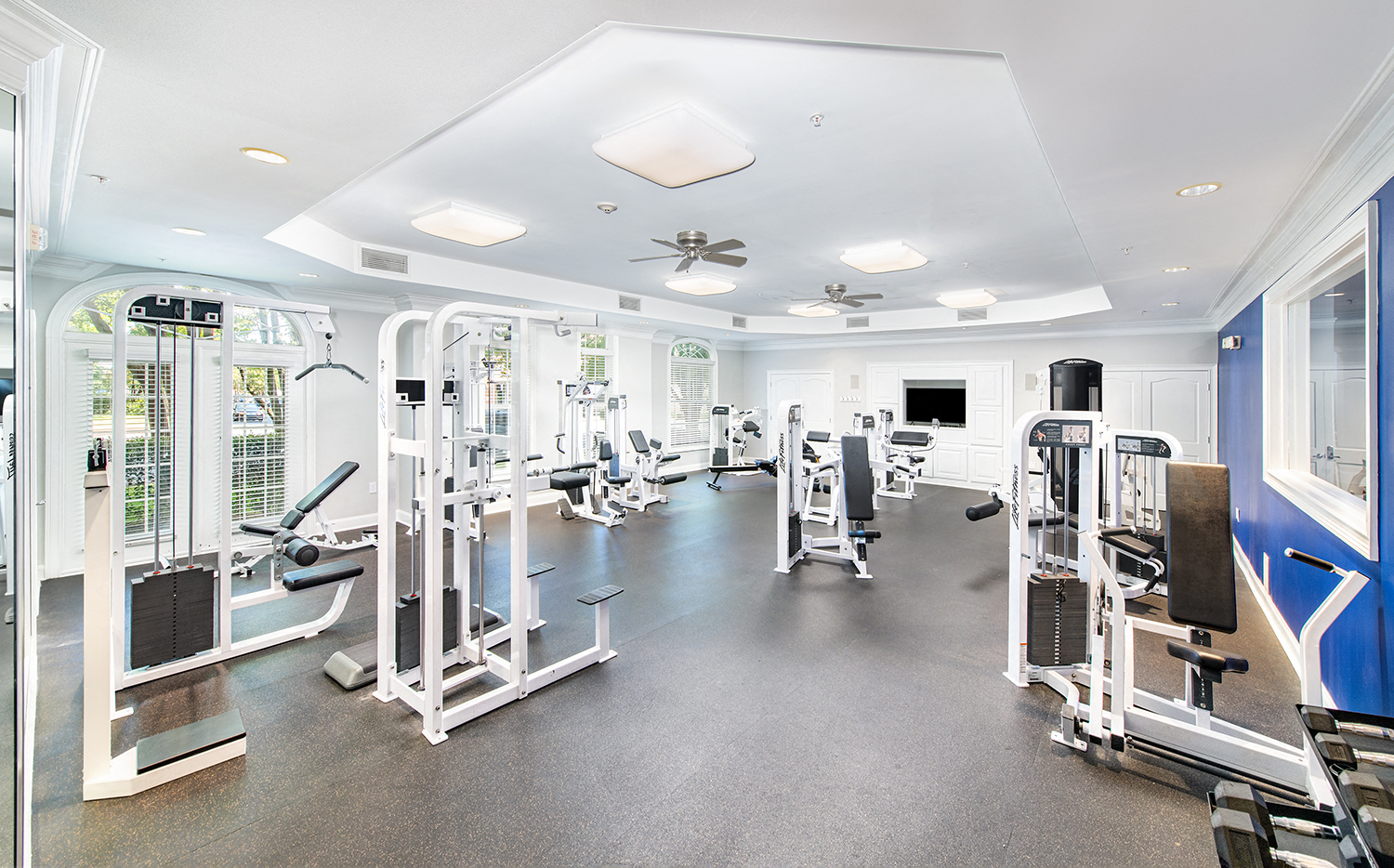 a generously sized gym with cardio equipment and windows