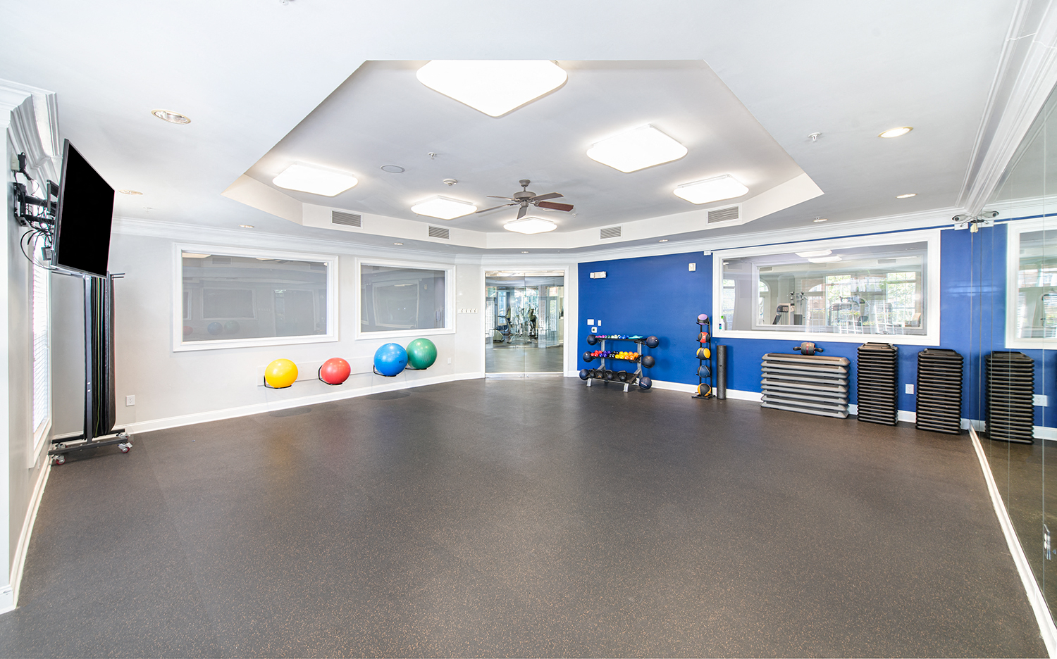 an empty gym with a ceiling fan and colorful balls on the floor