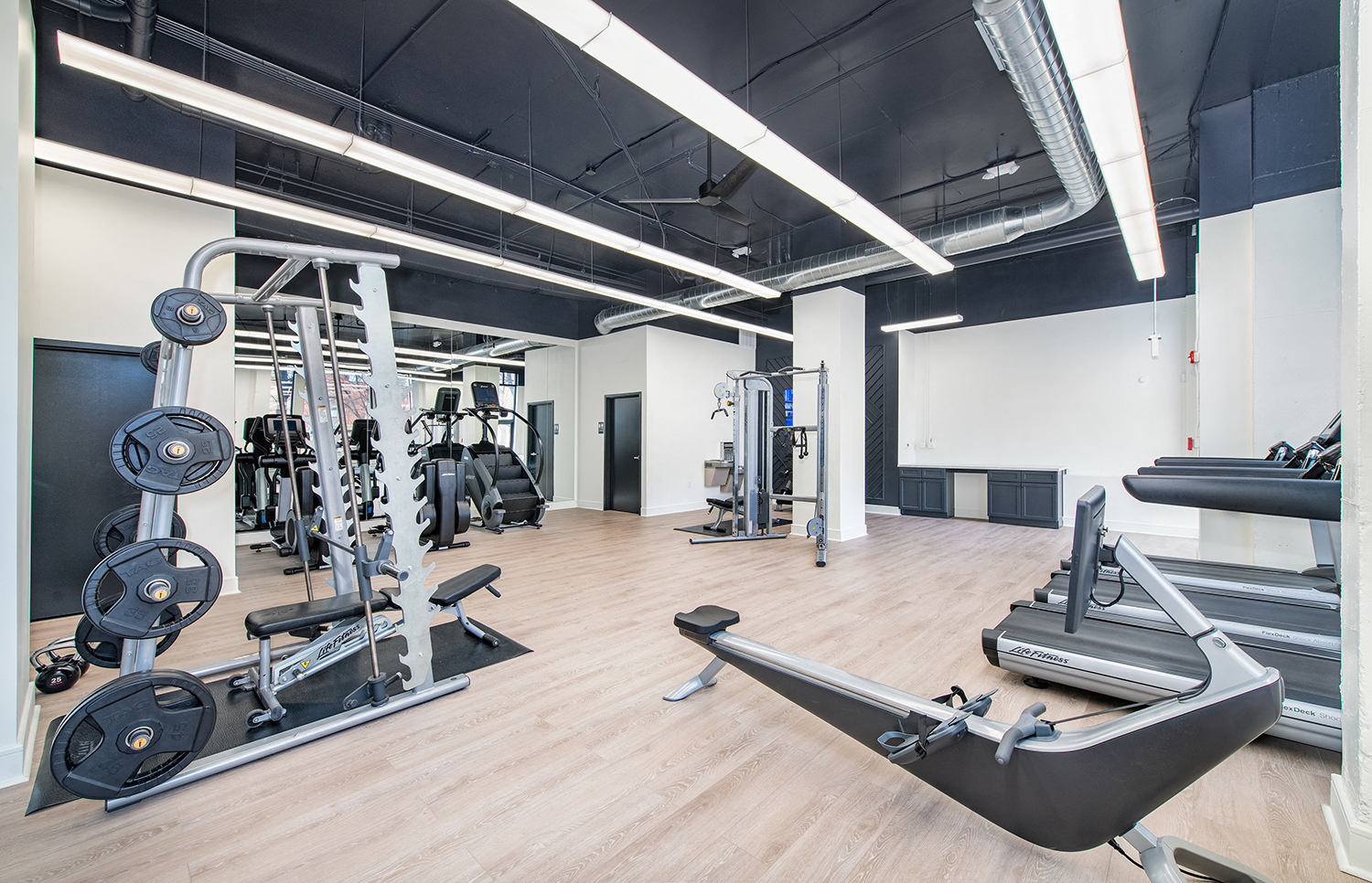 a gym with weights and other exercise equipment in a room with white walls and wood
