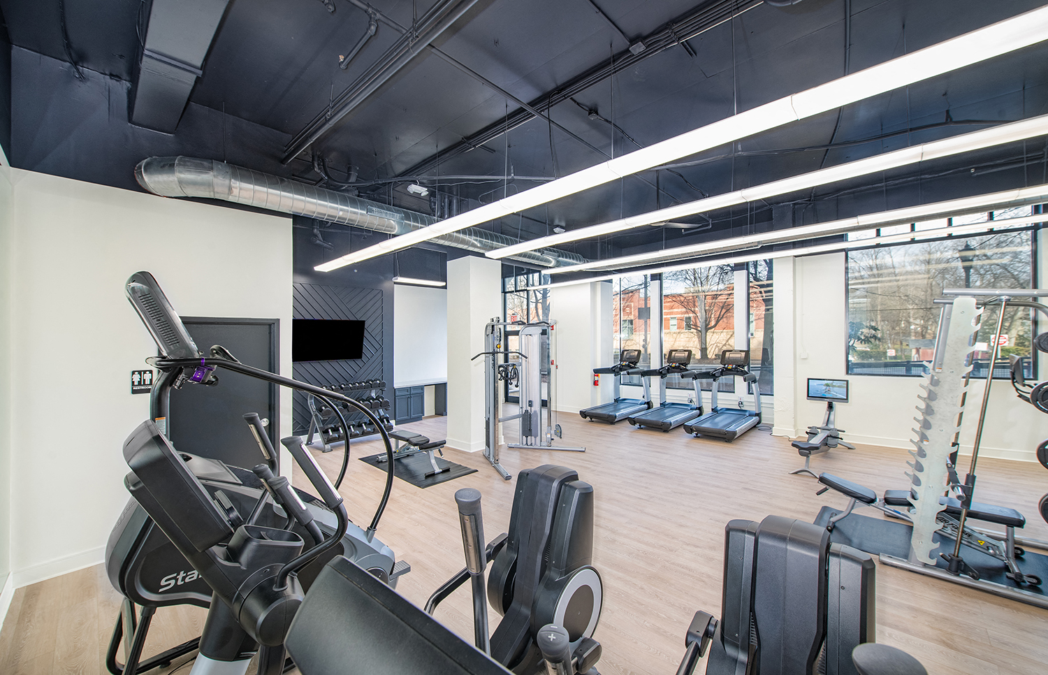 a gym with cardio machines and weights on a wooden floor