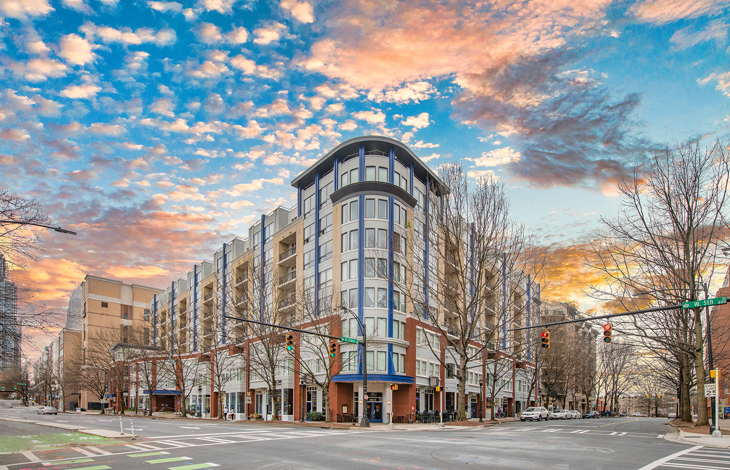 a building on the corner of a city street at sunset
