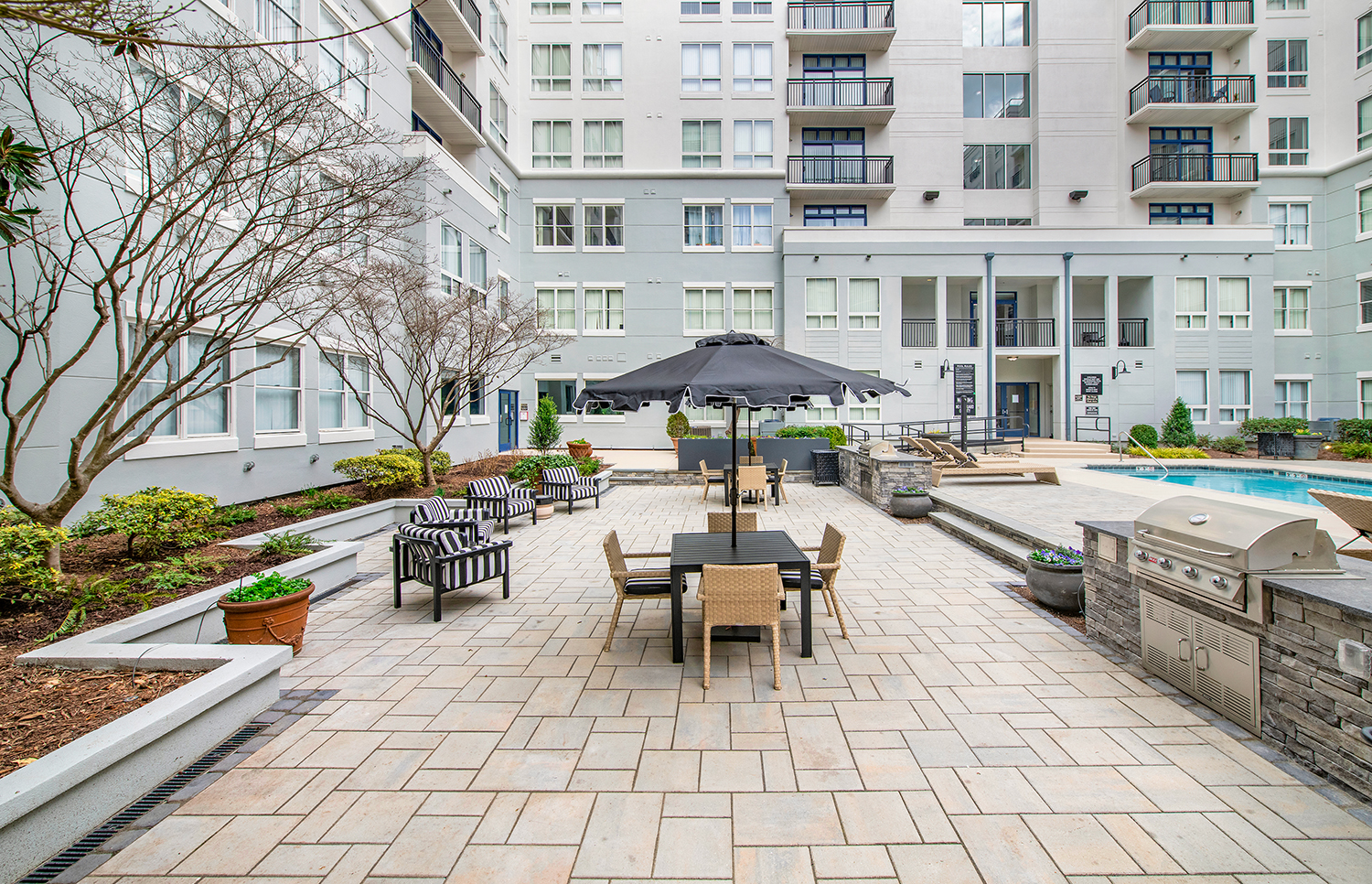 a patio with tables and umbrellas in front of an apartment building