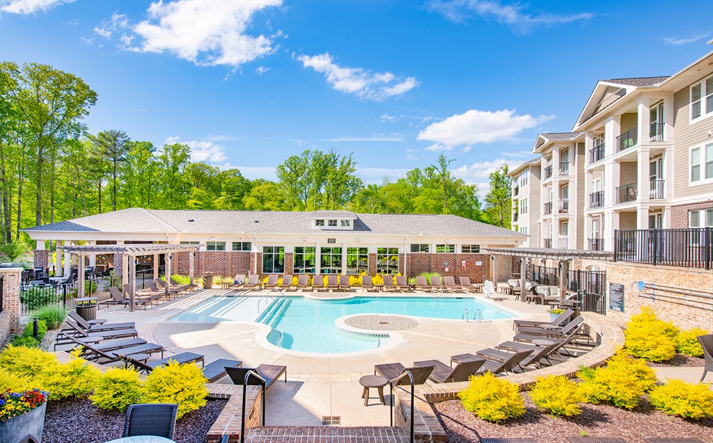 an outdoor pool with lounge chairs around it and an apartment building