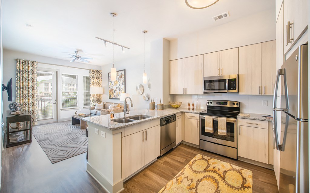 a kitchen with wooden floors and white cabinets and stainless steel appliances