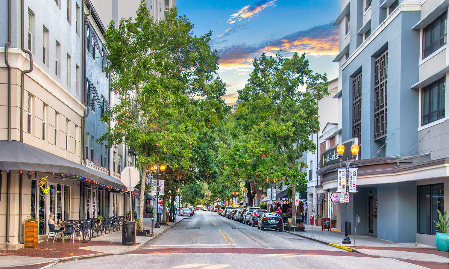 a city street with buildings and trees and a cloudy sky