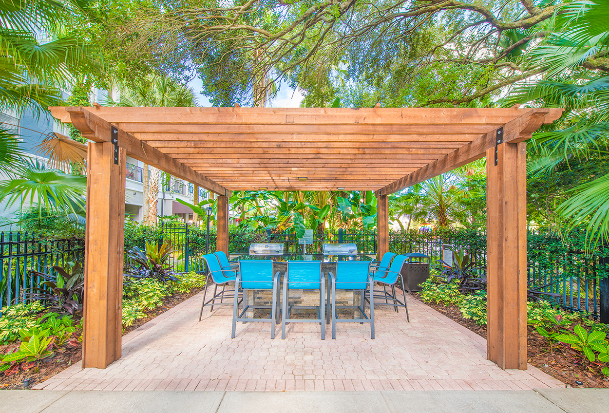 a patio with a table and chairs under a wooden pergola
