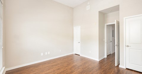 an empty bedroom with wood flooring and white walls