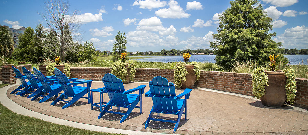 a patio with blue chairs and a lake in the background