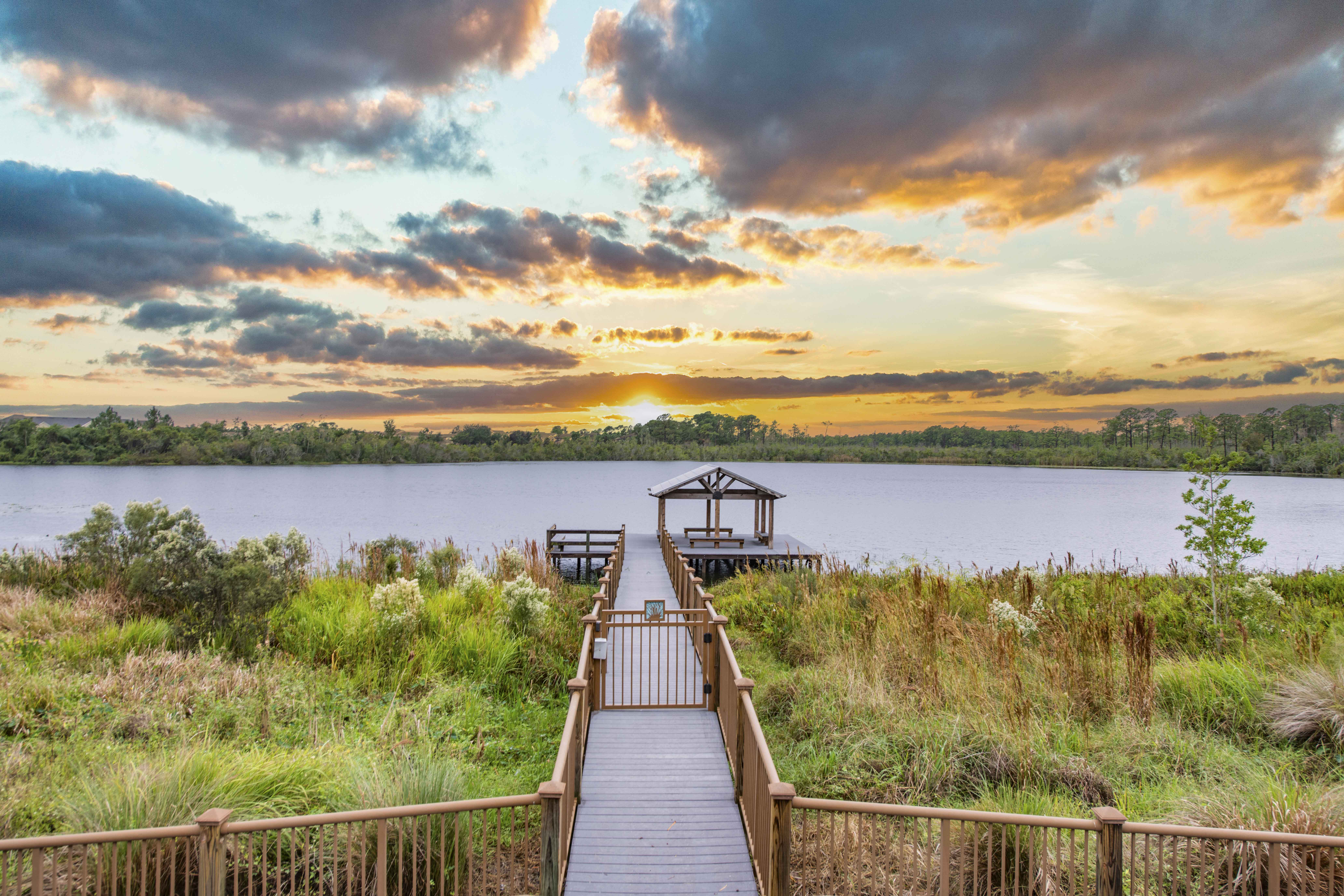 a dock on a lake with a sunset in the background