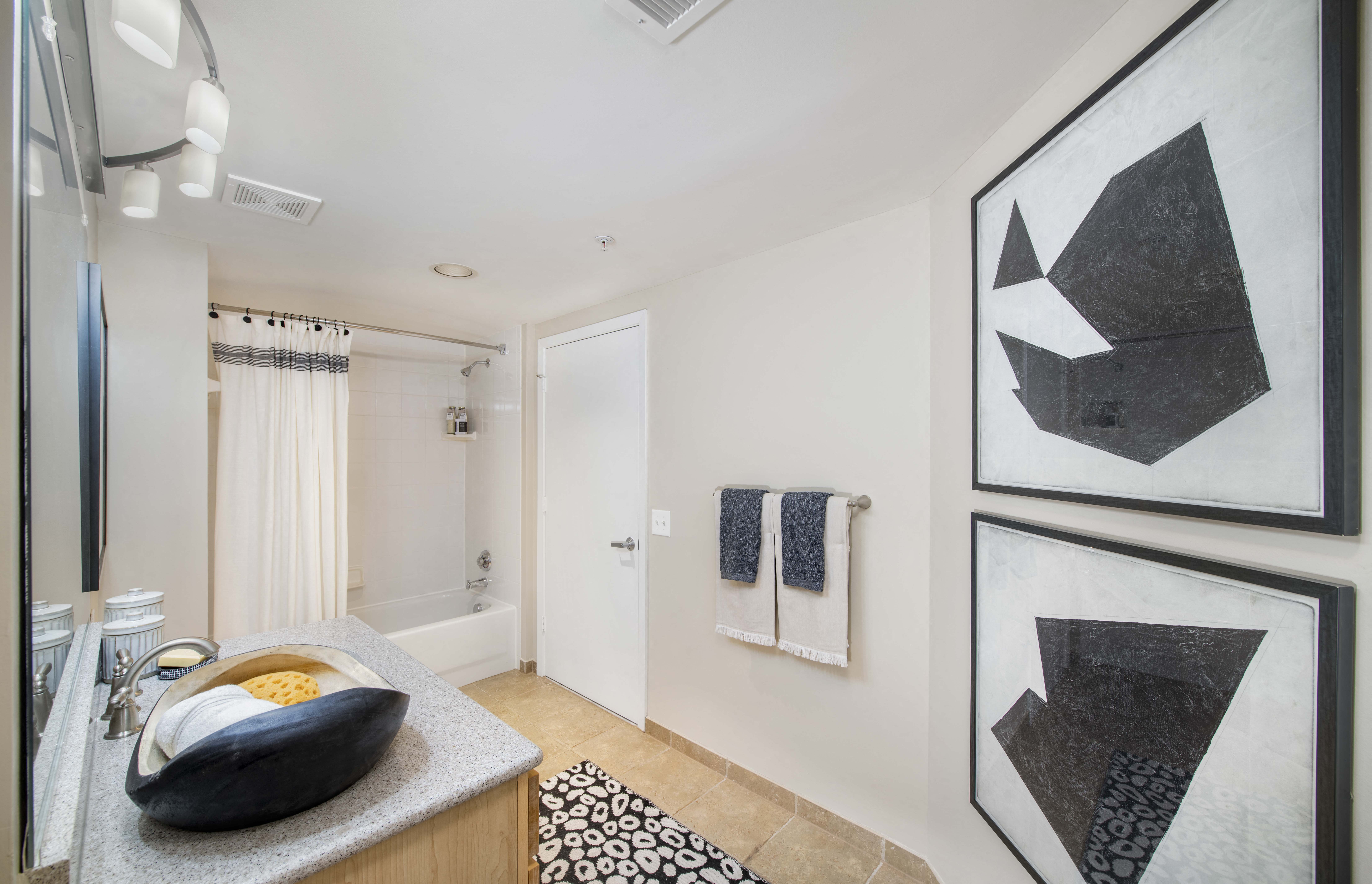 a bathroom with a sink and a shower and paintings on the wall