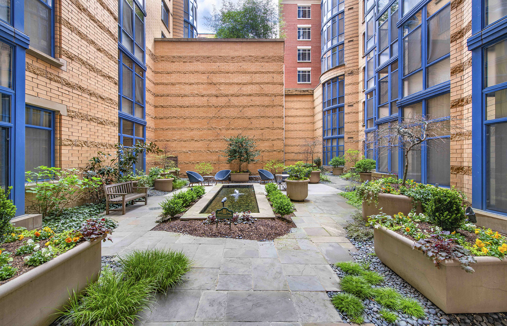 a courtyard with benches and plants in front of a brick building