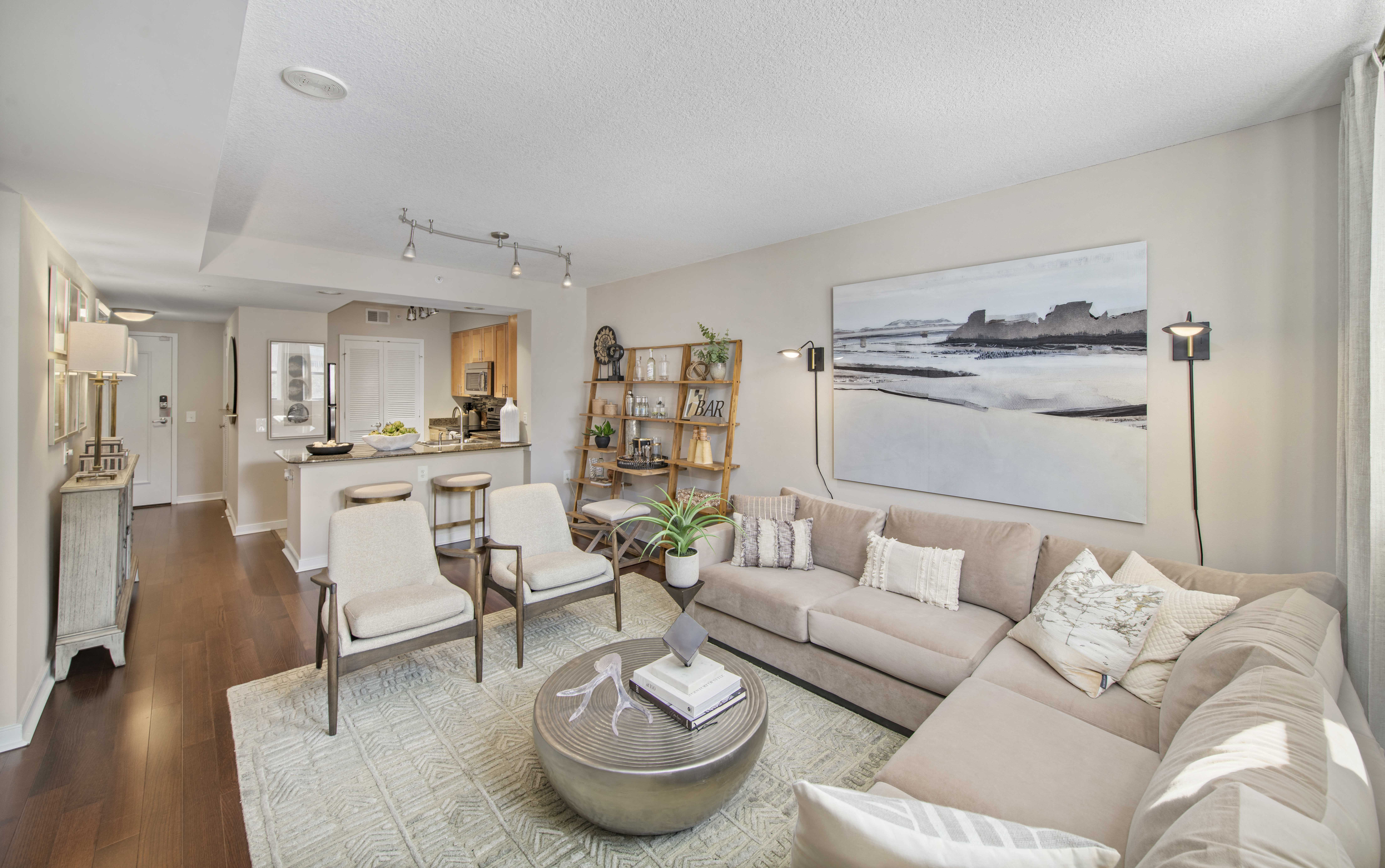 a living room with a couch and chairs and a kitchen in the background