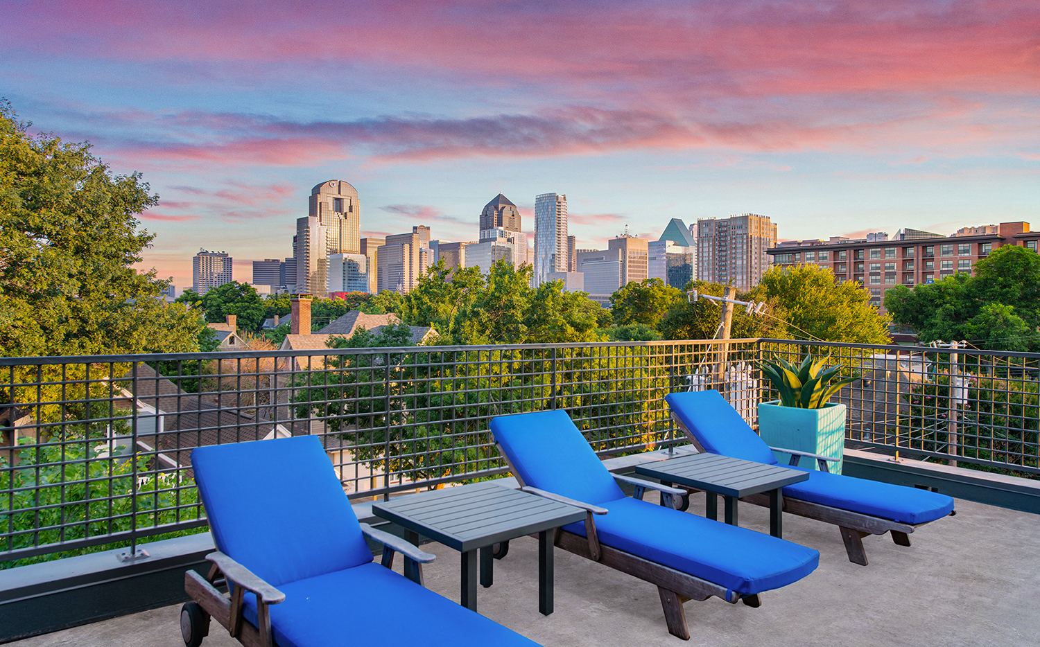 the city skyline is seen from the rooftop patio of a building with blue lounge chairs
