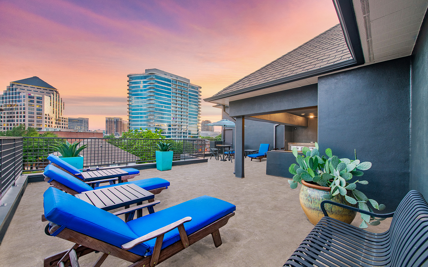 furnished patio with city skyline in the background and blue lounge chairs