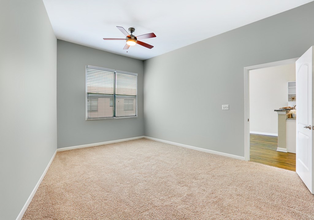 an empty room with a ceiling fan and a door to a bathroom