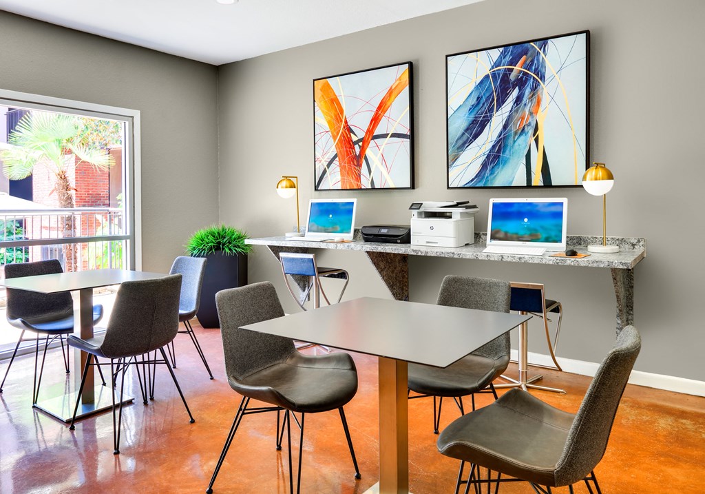 a conference room with tables and chairs and two computers on a desk