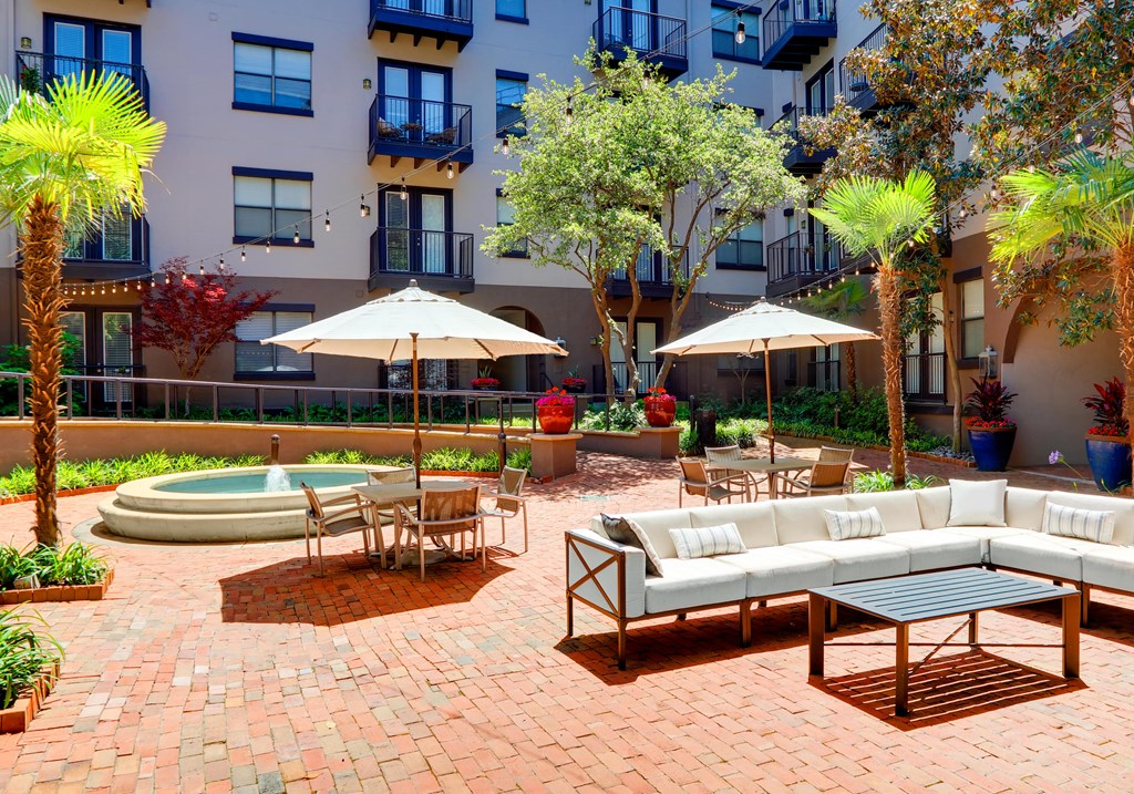 a patio with couches and tables in front of an apartment building