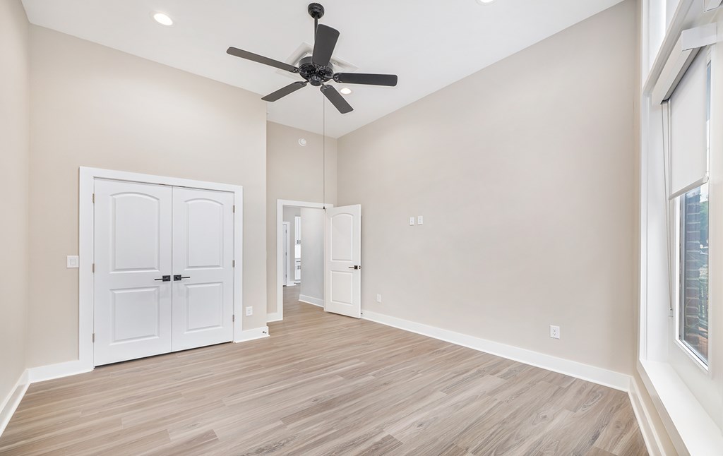 A room with a ceiling fan and wooden flooring.