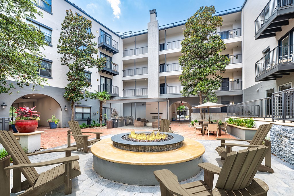 A courtyard with a fire pit surrounded by chairs.