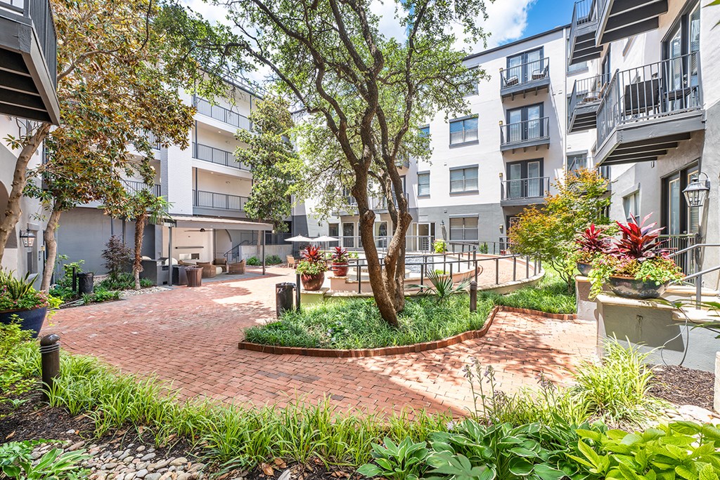 A courtyard with a tree and a bench in the middle.