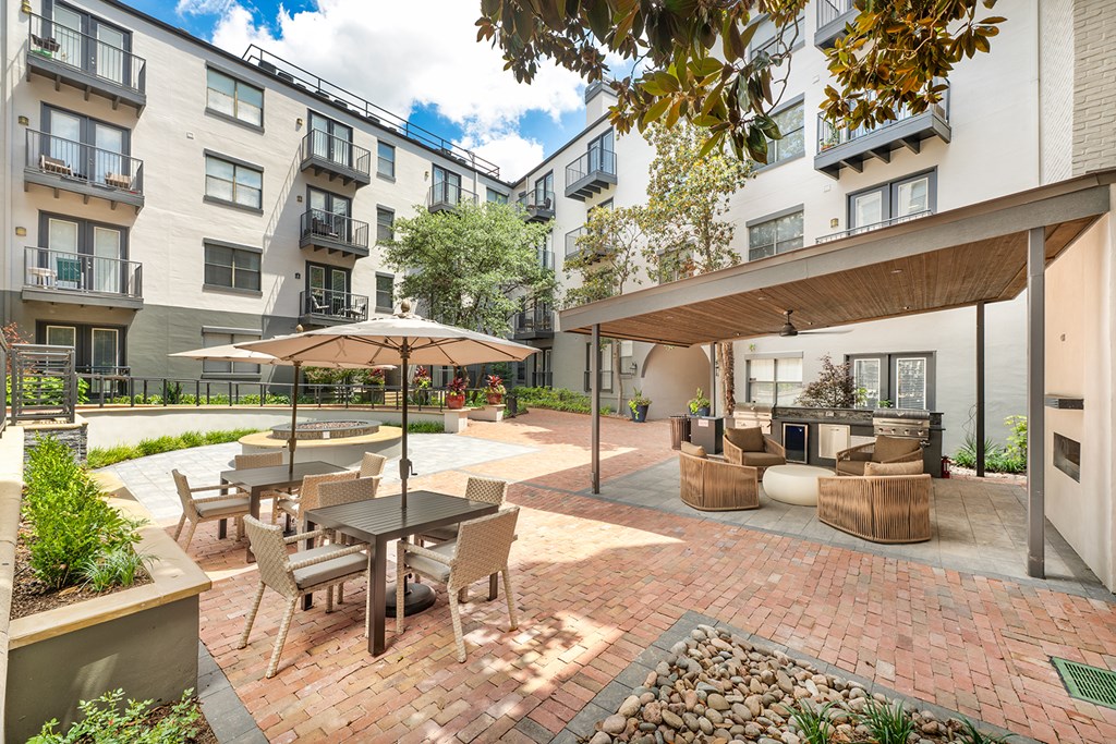 A patio with a table and chairs is surrounded by apartment buildings.