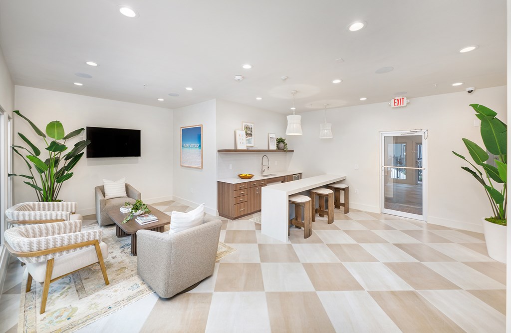 A spacious waiting room with a checkered floor and a flat screen TV mounted on the wall.