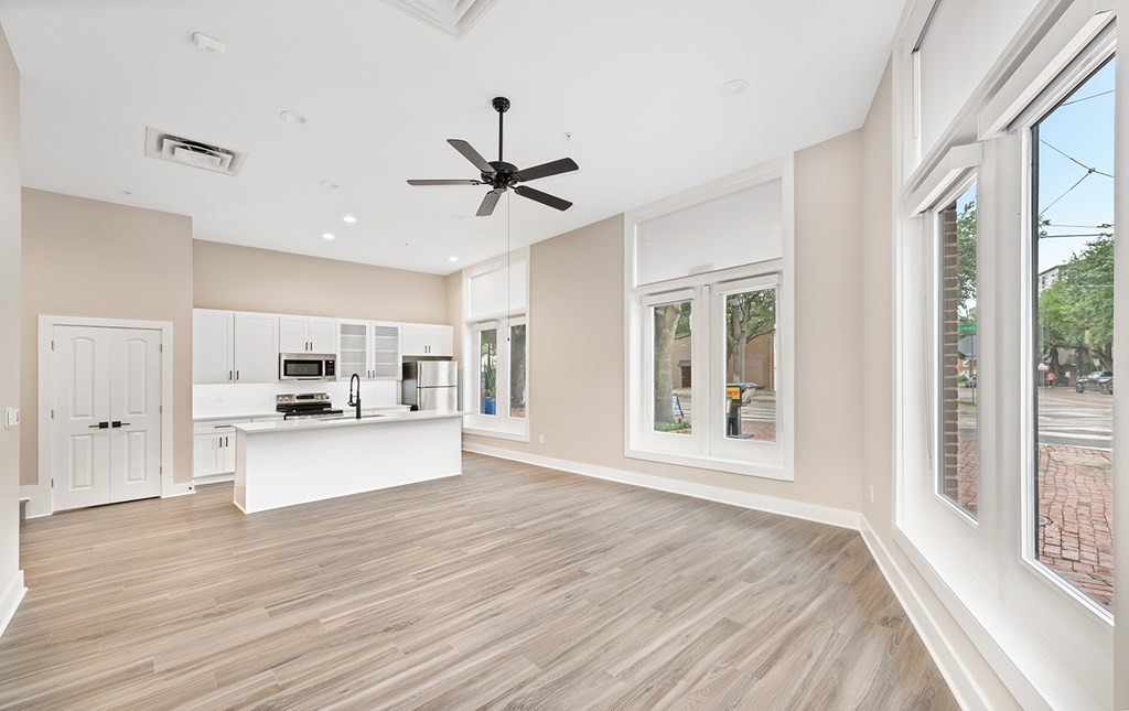 A spacious kitchen and living room with a ceiling fan and wooden flooring.