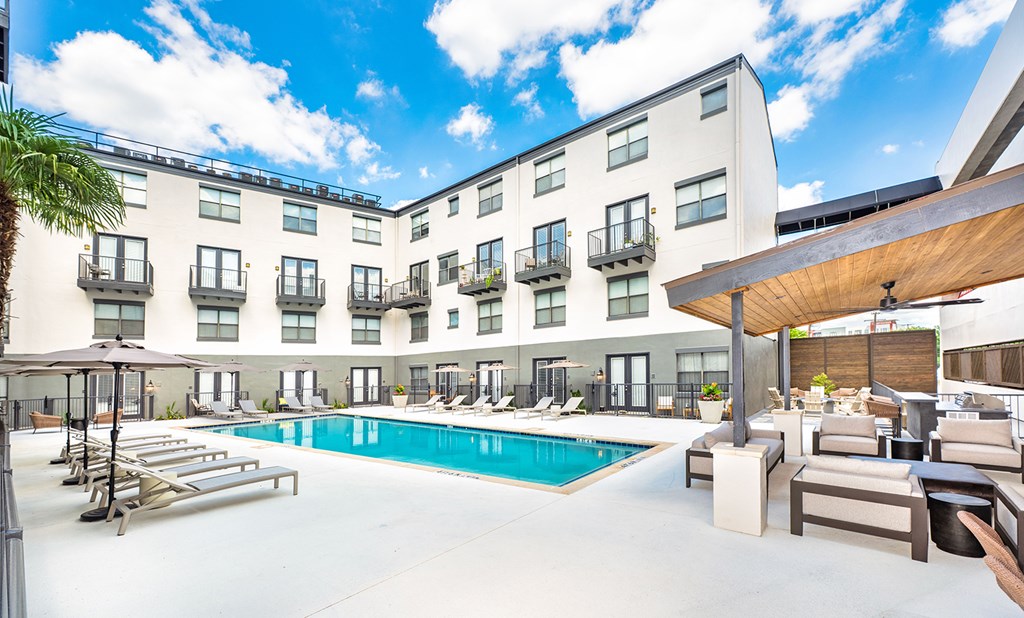 A large outdoor pool area with sun loungers and a wooden pergola.