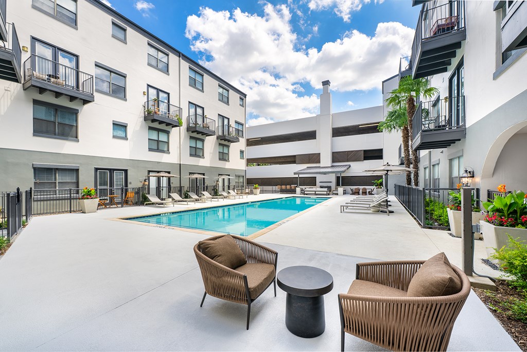 A pool area with chairs and a table.