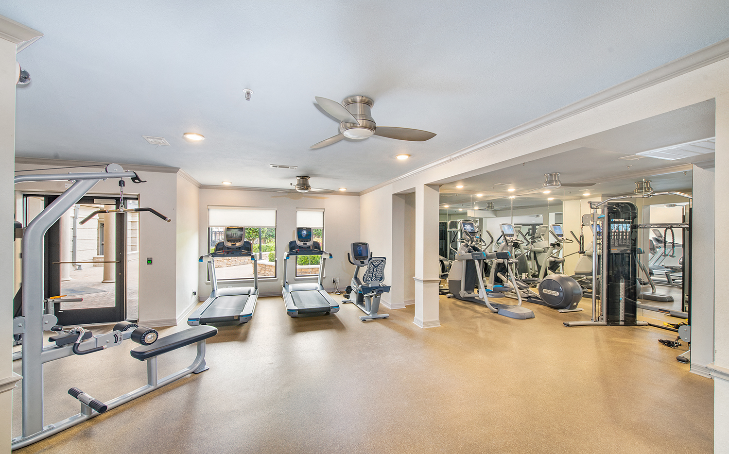 a gym with treadmills and weights in a home with a ceiling fan