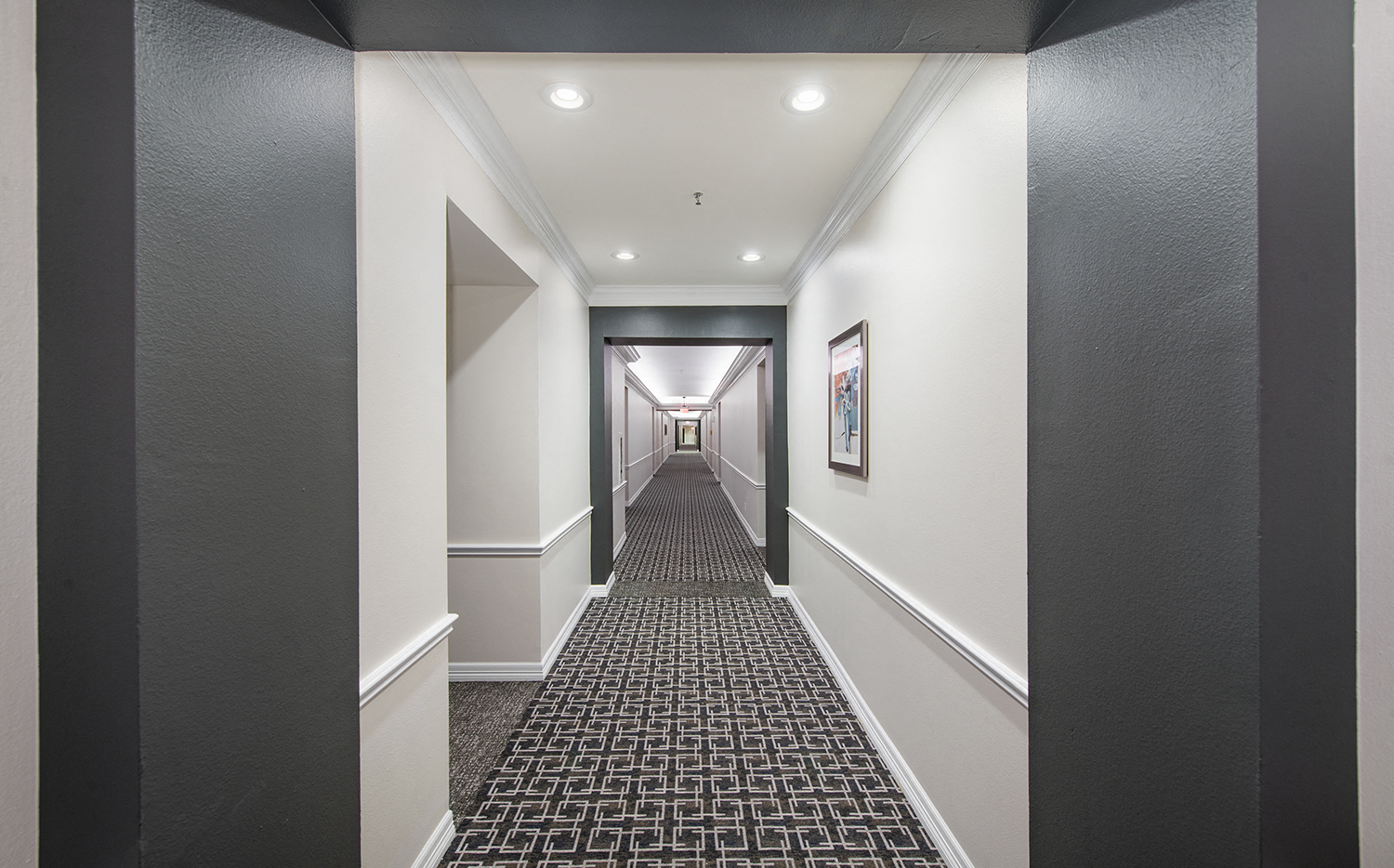 a long hallway with white walls and a black and white carpet