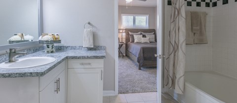 a bathroom with a sink and a shower and a bedroom with a bed