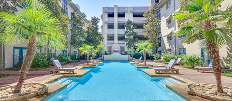a swimming pool with palm trees and a building in the background